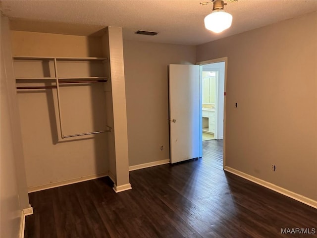 unfurnished bedroom featuring dark hardwood / wood-style flooring, a closet, and a textured ceiling