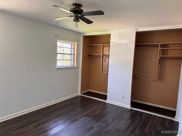 unfurnished bedroom with multiple closets, dark hardwood / wood-style floors, a textured ceiling, and ceiling fan