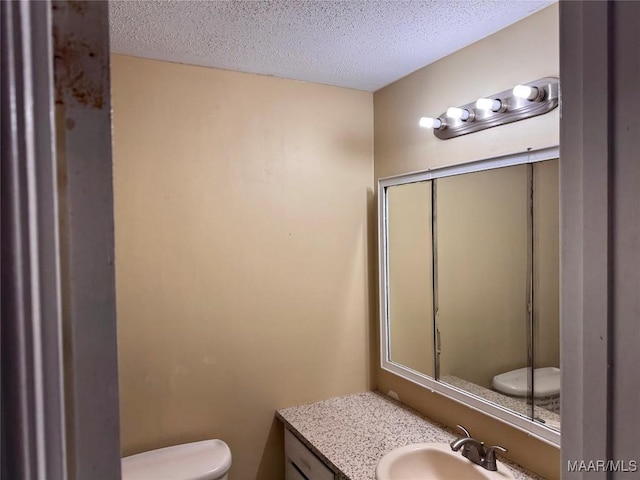 bathroom featuring vanity, a textured ceiling, and toilet