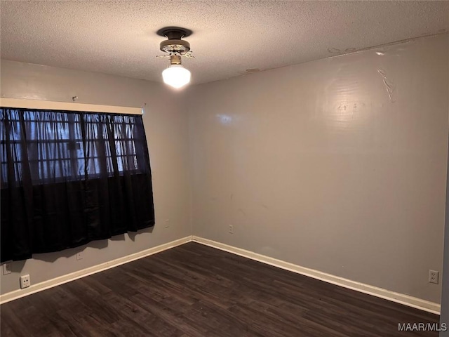 empty room with dark hardwood / wood-style floors and a textured ceiling