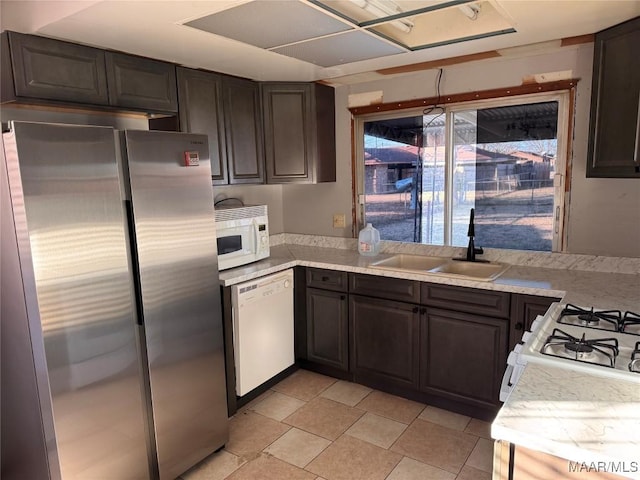 kitchen with dark brown cabinets, sink, and white appliances