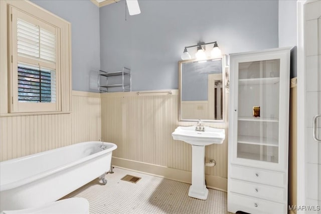 1311 Woodward Ave, Montgomery, AL 36106 - bathroom featuring a wainscoted wall, a freestanding tub, a ceiling fan, tile patterned floors, and a sink