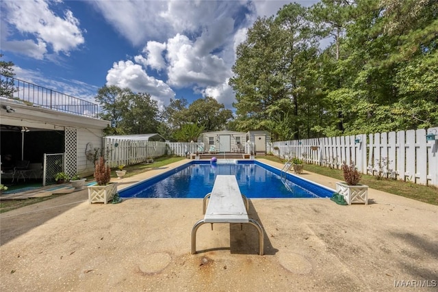 view of pool with a diving board and an outbuilding