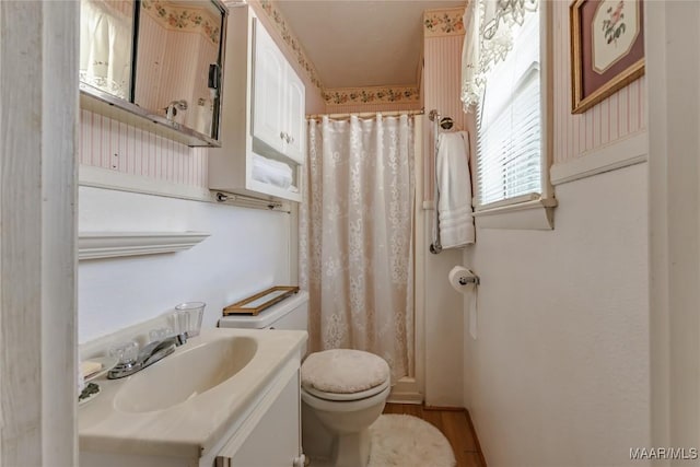 bathroom with hardwood / wood-style flooring, toilet, vanity, and walk in shower