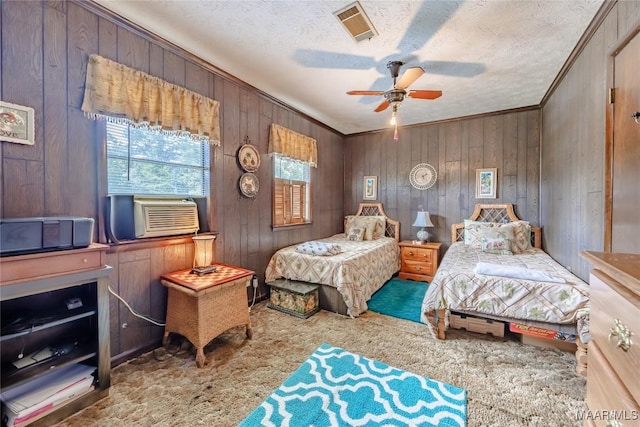 carpeted bedroom with ceiling fan, crown molding, cooling unit, a textured ceiling, and wooden walls