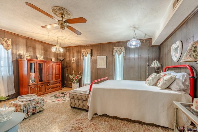 bedroom with a textured ceiling, carpet floors, ceiling fan, and wood walls