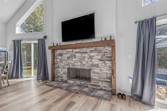 unfurnished living room featuring light hardwood / wood-style flooring, a fireplace, and high vaulted ceiling