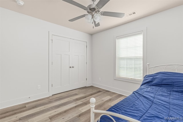 bedroom featuring light hardwood / wood-style floors, ceiling fan, and a closet