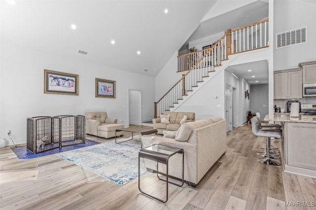 living room featuring light hardwood / wood-style flooring and high vaulted ceiling