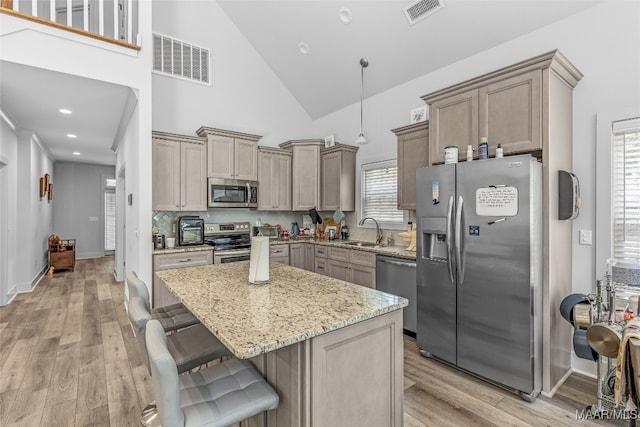 kitchen featuring light stone counters, sink, light hardwood / wood-style flooring, high vaulted ceiling, and appliances with stainless steel finishes