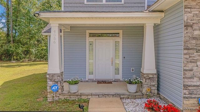 doorway to property featuring a yard and covered porch