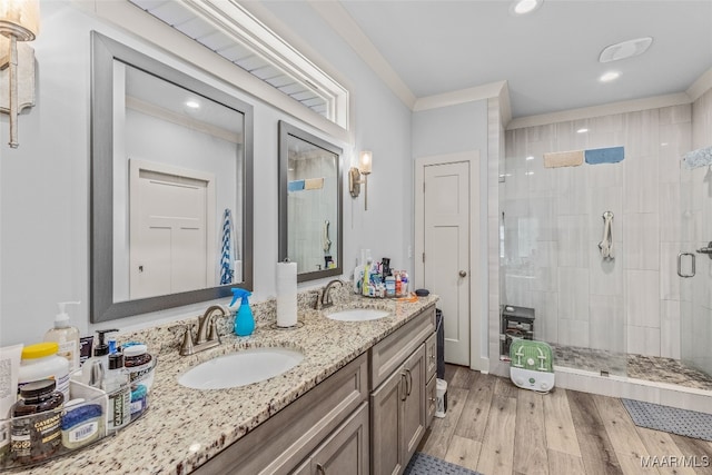 bathroom with ornamental molding, a shower with door, hardwood / wood-style flooring, and vanity