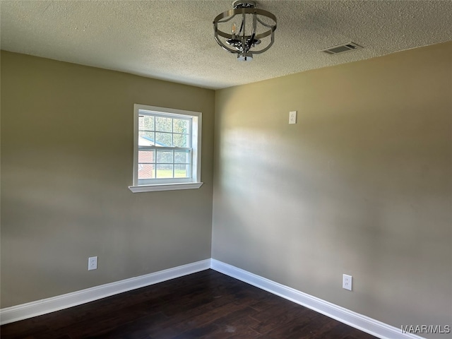 empty room with a textured ceiling and dark hardwood / wood-style floors