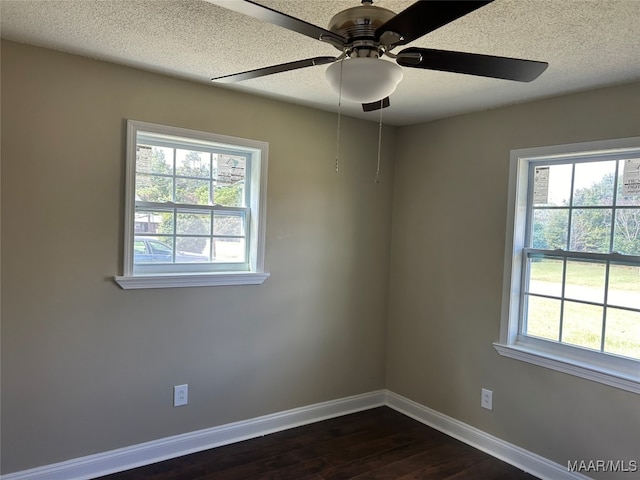 empty room with a textured ceiling, ceiling fan, dark wood-type flooring, and plenty of natural light