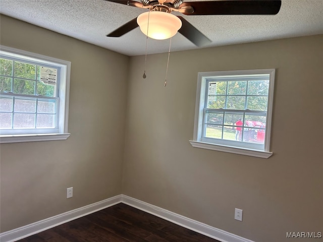 empty room with a textured ceiling, dark hardwood / wood-style flooring, ceiling fan, and plenty of natural light