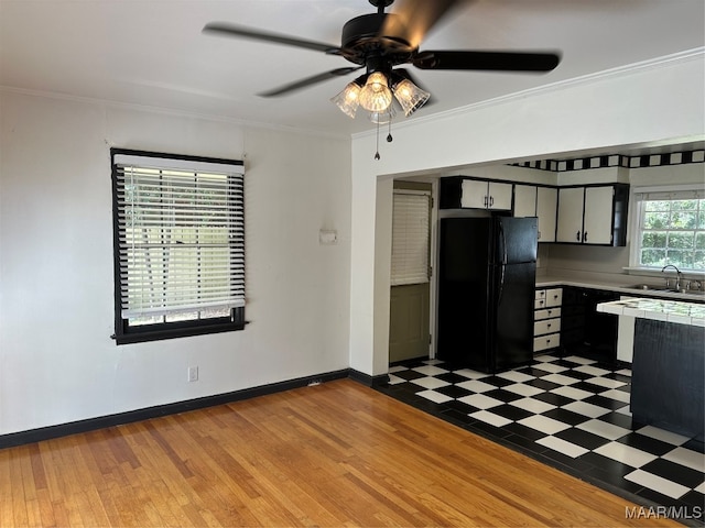 kitchen with light hardwood / wood-style flooring, sink, black fridge, and crown molding