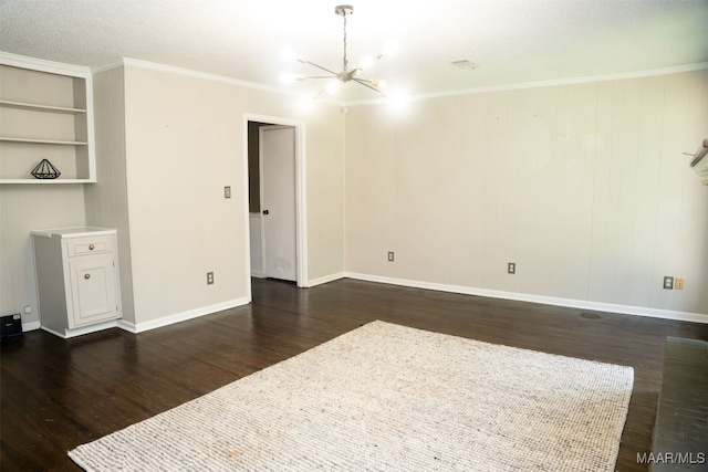 unfurnished room featuring built in shelves, ornamental molding, an inviting chandelier, and dark wood-type flooring