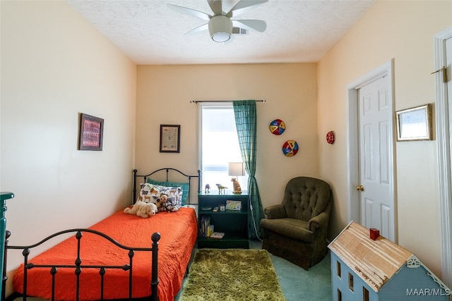 bedroom with ceiling fan, carpet floors, and a textured ceiling