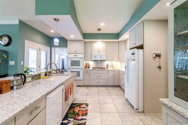 kitchen featuring light tile patterned flooring, pendant lighting, white appliances, sink, and light stone counters