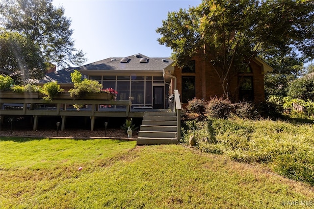 rear view of house featuring a deck, a sunroom, and a yard