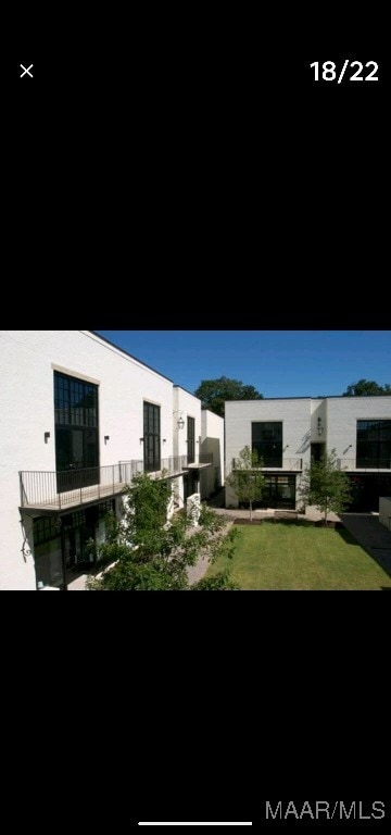 rear view of house with a balcony and a yard