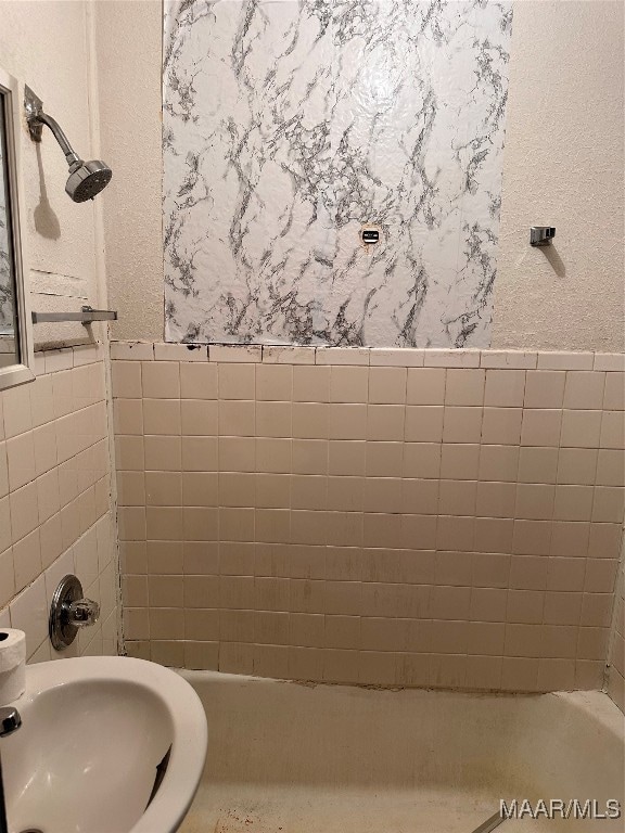 bathroom featuring bathing tub / shower combination, sink, and tile walls