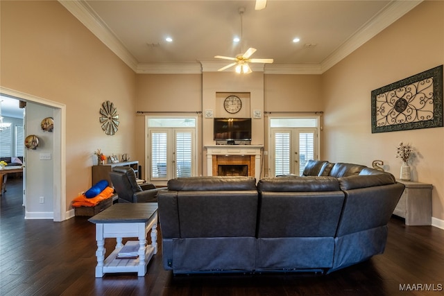 living room with ceiling fan, french doors, dark wood-type flooring, a tiled fireplace, and ornamental molding