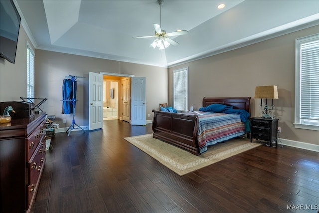 bedroom featuring ceiling fan, dark hardwood / wood-style floors, multiple windows, and a tray ceiling