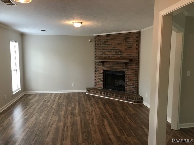 unfurnished living room with a brick fireplace, dark hardwood / wood-style floors, crown molding, and a textured ceiling