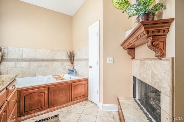 bathroom featuring vanity, a tile fireplace, tile patterned floors, and a tub