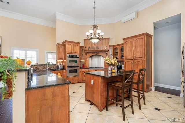 kitchen featuring crown molding, stainless steel double oven, a notable chandelier, a wall mounted AC, and a center island