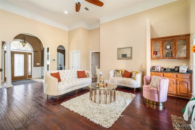 living room with ornate columns, crown molding, ceiling fan, and dark hardwood / wood-style flooring