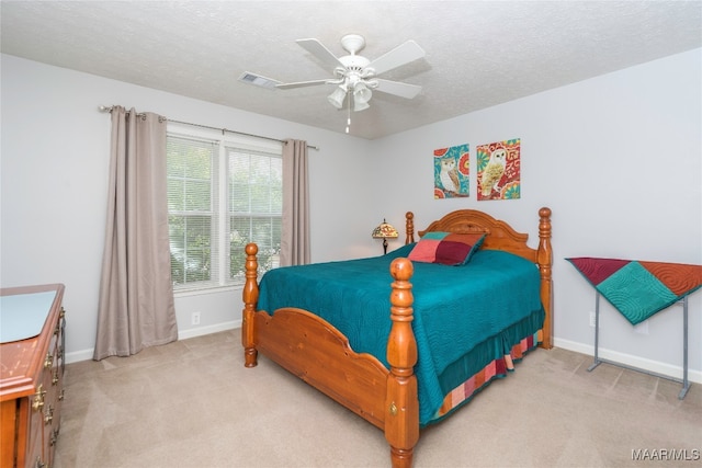 bedroom featuring light carpet, ceiling fan, and a textured ceiling