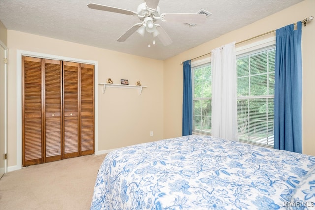 carpeted bedroom with ceiling fan, a textured ceiling, and a closet