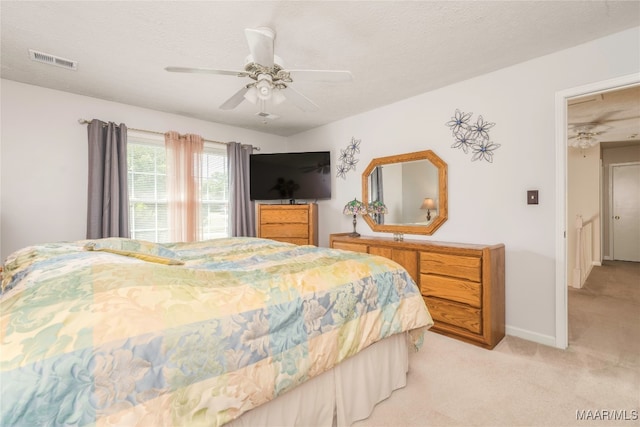 bedroom with ceiling fan, light colored carpet, and a textured ceiling