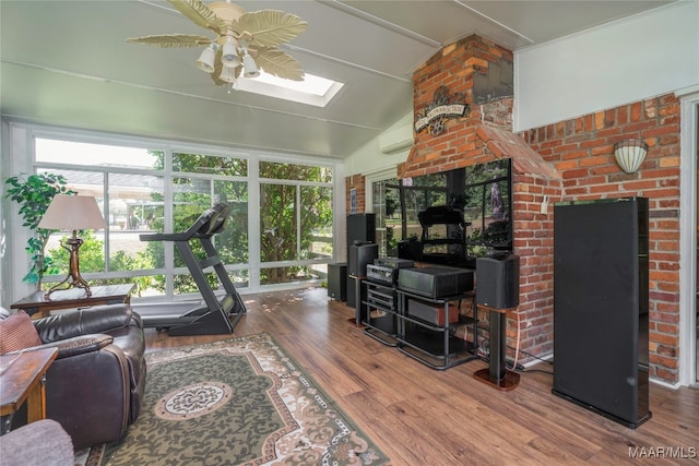 living room featuring lofted ceiling with skylight, a wall unit AC, ceiling fan, and wood-type flooring