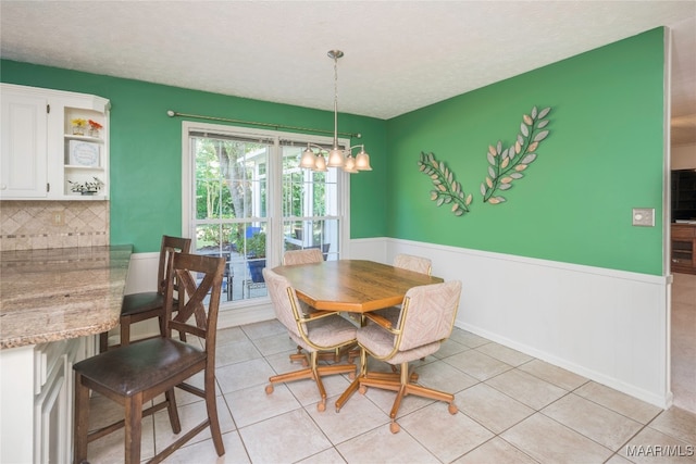 dining room with a notable chandelier, light tile patterned floors, and a textured ceiling