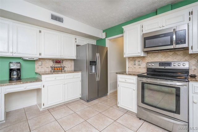 kitchen with appliances with stainless steel finishes, decorative backsplash, light tile patterned floors, and white cabinets