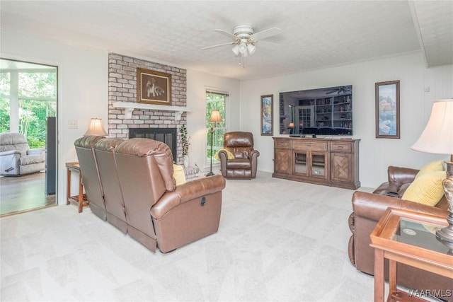 carpeted living room featuring a brick fireplace, ceiling fan, a textured ceiling, and a healthy amount of sunlight