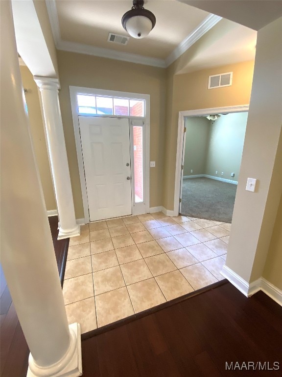 entrance foyer featuring ornate columns, light tile patterned flooring, and ornamental molding