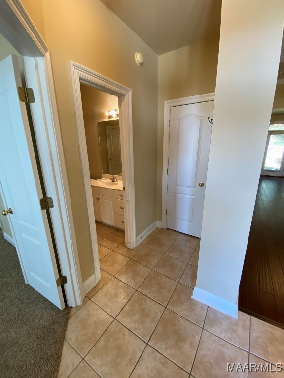 corridor featuring sink and light tile patterned floors