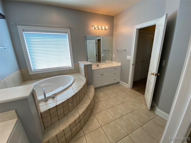 bathroom with tile patterned flooring, tiled bath, and vanity