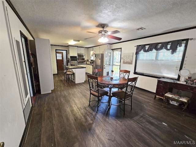 dining area featuring dark wood-type flooring, a textured ceiling, ceiling fan, and ornamental molding