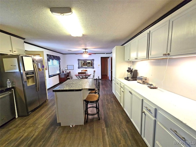 kitchen featuring a textured ceiling, a center island, dark hardwood / wood-style flooring, a breakfast bar, and appliances with stainless steel finishes