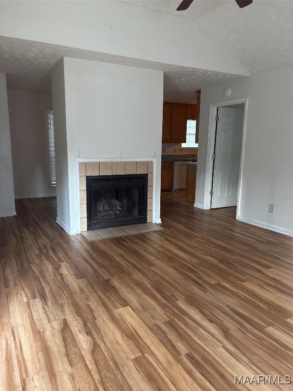 unfurnished living room with dark wood-type flooring, ceiling fan, a textured ceiling, and a tile fireplace