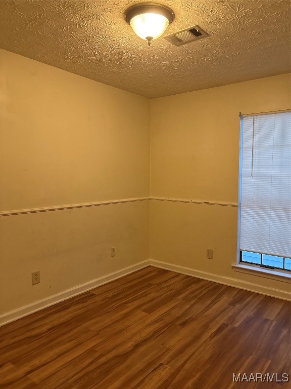 unfurnished room with a textured ceiling and dark hardwood / wood-style flooring