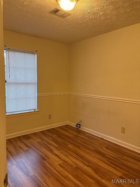 spare room featuring a textured ceiling and hardwood / wood-style flooring