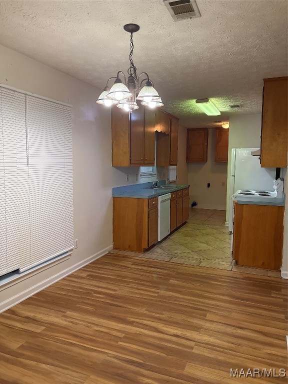 kitchen featuring a chandelier, a textured ceiling, dishwasher, and light wood-type flooring