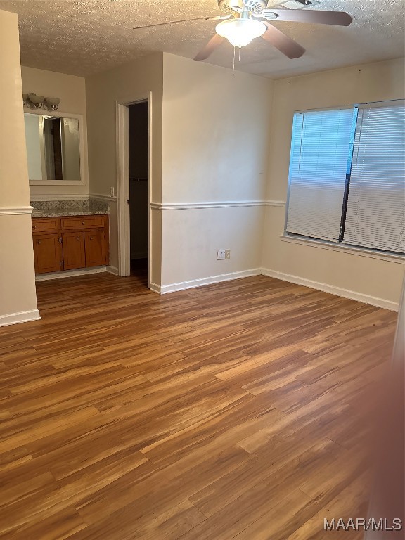 spare room featuring a textured ceiling, hardwood / wood-style flooring, and ceiling fan