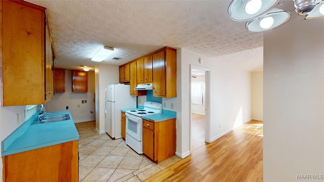 kitchen featuring white appliances, light hardwood / wood-style floors, a textured ceiling, and sink